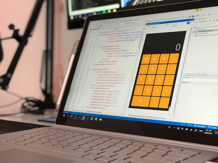 The image shows an open laptop placed on a wooden desk in a well-lit room. The laptop screen displays lines of code, indicating a programming or coding activity. The keyboard is visible, and the surro